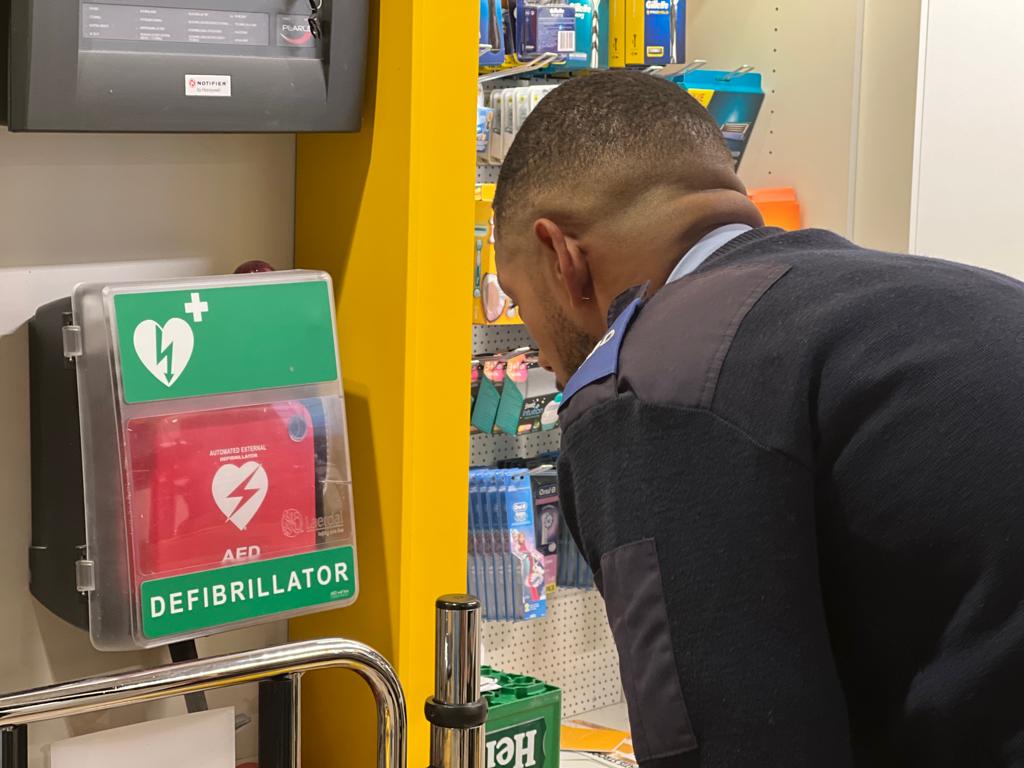 Huschka winkelbeveiliger pakt AED voor noodsituatie.